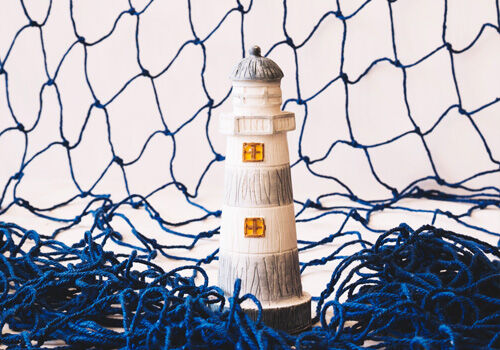 Schutznetz nach Maß – langlebig, zertifiziert und vielseitig einsetzbar Dekorativer Leuchtturm mit blauem Netz im maritimen Stil